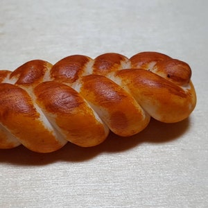 Könnte beinhalten: Ein geflochtenes Brotlaib mit einer goldbraunen Kruste.