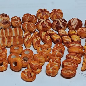 Könnte beinhalten: Eine Sammlung verschiedener Brotsorten, darunter Brötchen, Baguettes, Brezeln und Laib, alle goldbraun gebacken.