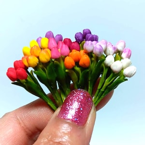 May include: A bunch of miniature artificial tulips in a variety of colours, including red, orange, yellow, pink, purple and white. The tulips are made from polymer clay and have green stems and leaves.