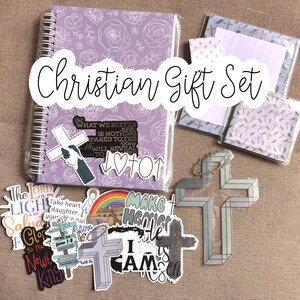 May include: A Christian gift set with a purple notebook, stickers, and a cross-shaped ornament. The stickers feature religious quotes and imagery, including a rainbow, a cross, and the words "Make Heaven Your Home".