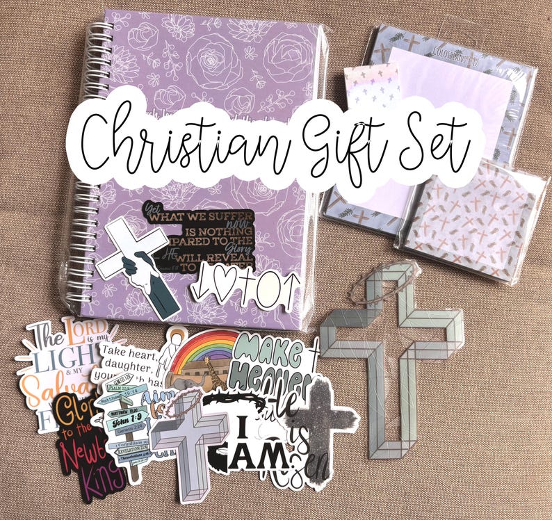 May include: A Christian gift set with a purple notebook, stickers, and a cross-shaped ornament. The stickers feature religious quotes and imagery, including a rainbow, a cross, and the words "Make Heaven Your Home".