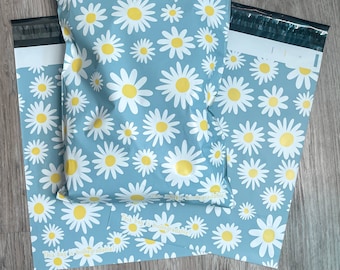 May include: Two blue and white patterned poly mailers with the text "This bag is biodegradable" printed on them. The mailers feature a white daisy pattern on a light blue background.