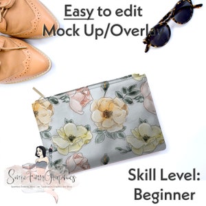 Könnte beinhalten: Eine graue Reißverschlusstasche mit einem Blumenmuster aus gelben, rosa und grünen Aquarellrosen. Die Tasche liegt auf einer weißen Oberfläche mit einem Paar braunen Lederschuhen und einer Sonnenbrille.