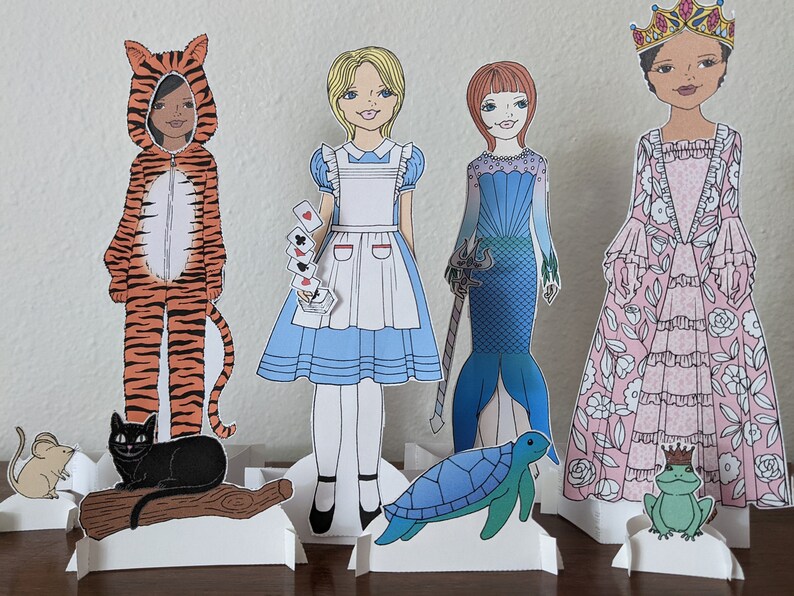 May include: Paper dolls of a tiger, Alice in Wonderland, a mermaid, and a princess. Each doll has a separate stand and accessories. The accessories include a cat, a mouse, playing cards, a trident, a sea turtle, and a frog.