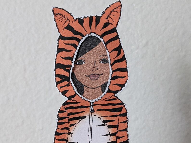 May include: A child wearing a tiger costume with orange and black stripes. The costume has a hood with ears and a zip in the front.