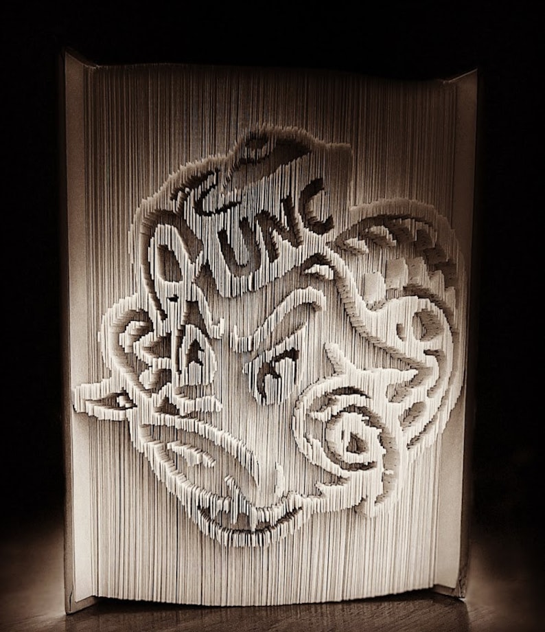 May include: A 3D paper art sculpture of a dragon's head, created by folding pages of a book. The dragon's head is made of white paper and has a detailed design.