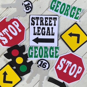 May include: A set of 16th birthday party decorations featuring a stop sign, a street legal sign with an arrow, a traffic light, a key, and a sign that says "George".