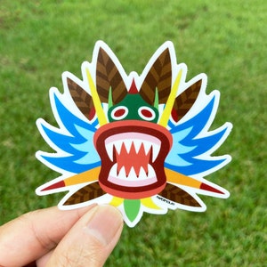 May include: A colorful sticker of a dragon head with a wide open mouth, sharp teeth, and blue wings. The dragon's head is green, red, and yellow. The sticker has the text "PAPEROLAS" at the bottom.