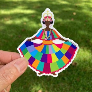 May include: A colorful sticker featuring a stylized illustration of a person in a vibrant dress. The dress is a patchwork of rainbow colors, and the person wears a crown and jewelry. The sticker has the text "PAPERMOLAS" on the right side.