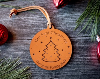 May include: A brown leather Christmas ornament with the text "Our First Christmas The Smith Family 2021" and a stylized Christmas tree design.