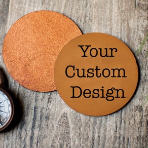 May include: Two brown leather coasters, one with the text "Your Custom Design" and the other plain.