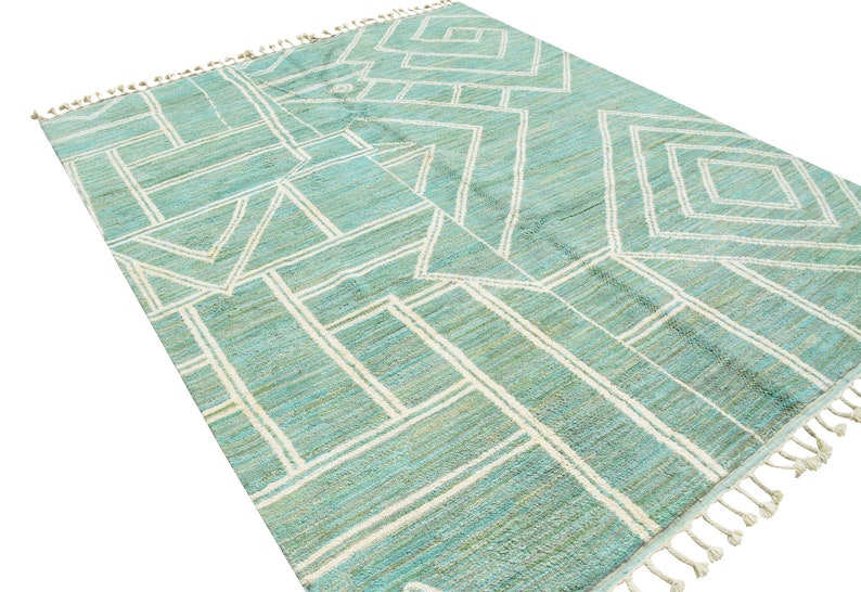 May include: A teal and white geometric patterned rug with a fringe border.
