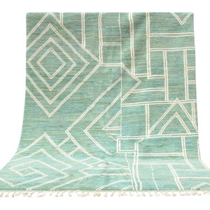 May include: A teal and white geometric patterned rug with fringe on the edges.