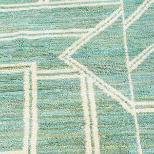 May include: A close-up of a teal and white patterned rug with a geometric design. The rug has a soft, textured surface.