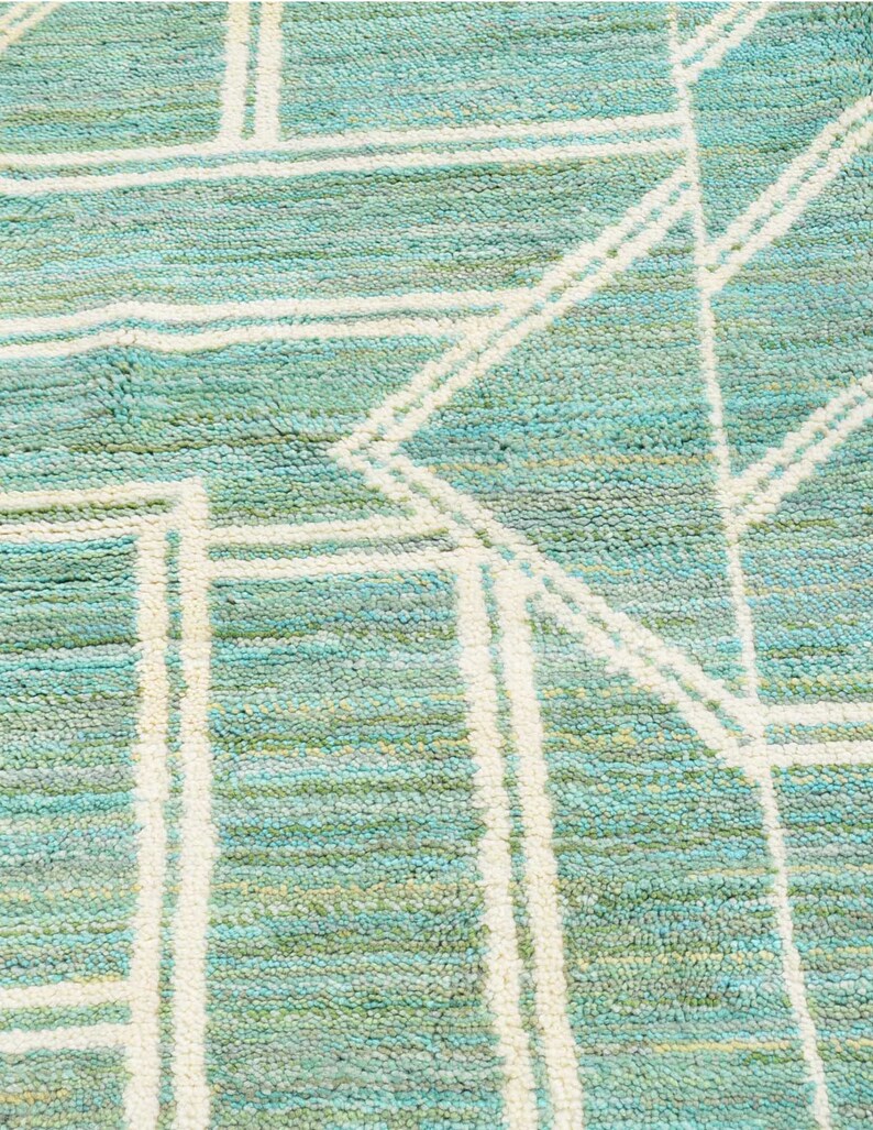 May include: A close-up of a teal and white patterned rug with a geometric design. The rug has a soft, textured surface.