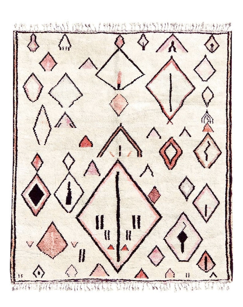 May include: A cream-colored rug with a geometric pattern in shades of pink and black. The pattern features diamonds, triangles, and lines.