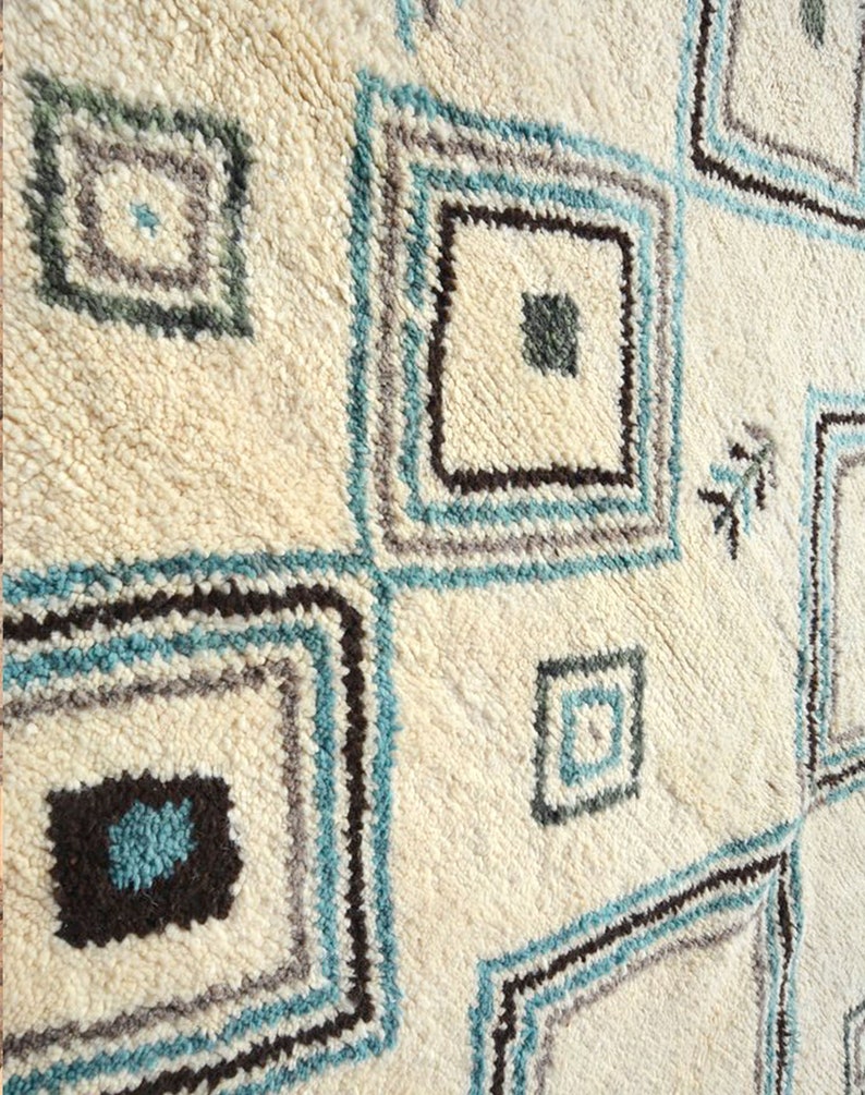 May include: A white rug with a geometric pattern of squares in shades of blue, brown, and gray.