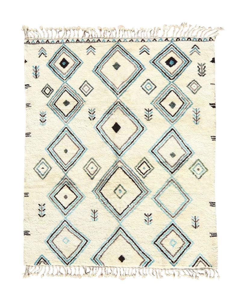 May include: A white rug with a geometric pattern of blue and black diamonds. The rug has a fringe border.