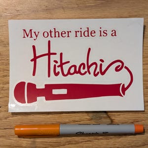 以下が含まれることがあります： 「My other ride is a Hitachi」という赤い文字と、赤いマイクのシルエットが描かれた白いステッカーです。