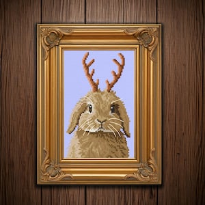May include: A brown rabbit with a pair of antlers, framed in a gold frame against a light purple background.