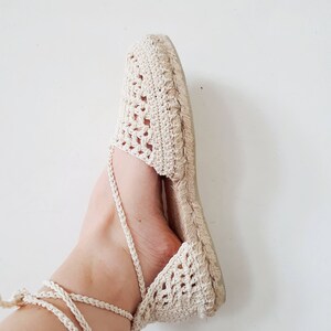 May include: A pair of cream-coloured crocheted espadrilles with a lace-up ankle strap.