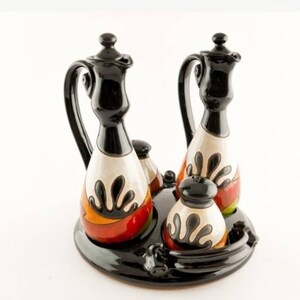 May include: A set of four ceramic oil and vinegar cruets with a black and white geometric design. The cruets are on a black tray with a raised rim. The cruets have a black and white geometric design with orange, red, and green accents.