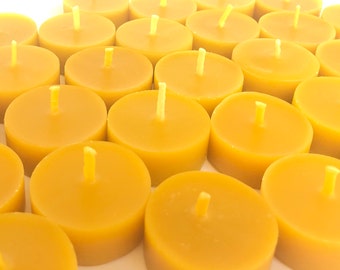 May include: A close-up view of a group of round, yellow tea light candles. The candles are arranged in a grid pattern and are all lit.