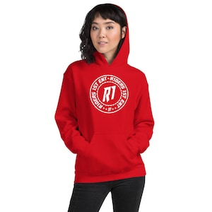 May include: A red hoodie featuring a white circular logo with the text "R1 RIDERS 1ST ENT". The sweatshirt has a front pocket and a drawstring hood. The person in the image is wearing black trousers.