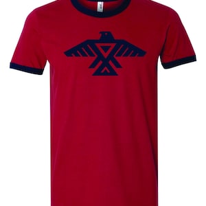 May include: Red t-shirt with a navy blue ringer and a navy blue stylized eagle graphic.