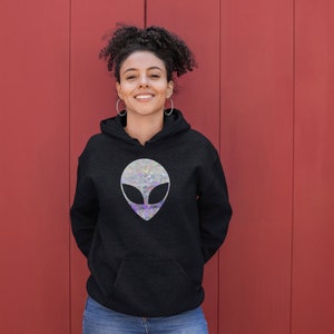May include: A black hoodie featuring a silver alien head graphic. The alien head has a holographic finish.