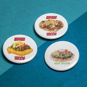 May include: Three white round buttons with images of Indian tacos. The top button says "INDIAN TACOS" in red text. The left button says "INDIAN TACOS" in red text. The right button says "NDN TACOS" in green text.