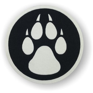 May include: A white paw print on a black circular background. The paw print is a simple design with four toes and a large pad.