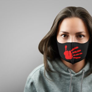 May include: A person wearing a black face mask with a red handprint design. The handprint is covering the mouth area of the mask.