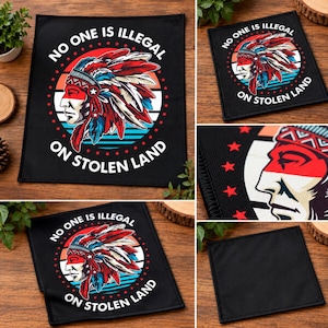 May include: A square black fabric patch featuring a graphic of a person wearing a traditional feathered headdress in red, white, and blue. The text NO ONE IS ILLEGAL ON STOLEN LAND is printed in white around the circular design with red stars.