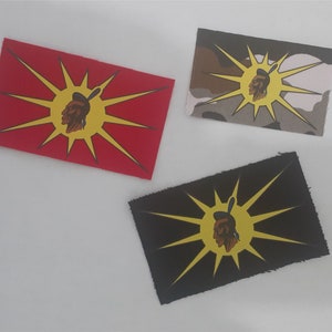 Peut inclure: Trois patchs en tissu avec un motif de profil amérindien au centre d'un soleil jaune. Les patchs sont sur un fond blanc. Les patchs sont rouge, camouflage et noir.