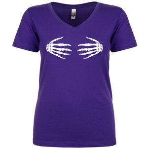 May include: Purple v-neck t-shirt with a white skeleton hand graphic. The hands are positioned as if they are covering the chest.