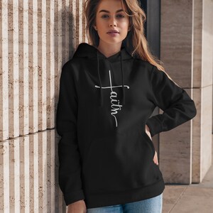 May include: A black hoodie with a white cross and the word "faith" written vertically on the front.
