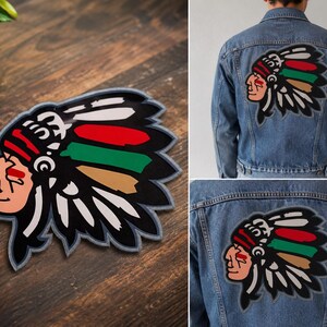May include: A large embroidered patch featuring a profile illustration of a person wearing a traditional feathered headdress. The design includes bold red, green, and tan accents against a black and white background, shown applied to a denim jacket.