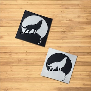May include: Two black and white wolf silhouette stickers. The wolf is howling at the moon. The stickers are on a wooden background.