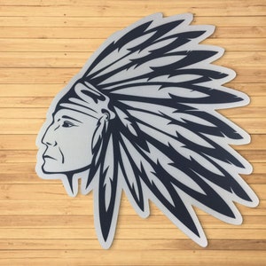 May include: A black and white illustration of a Native American man wearing a headdress with feathers. The image is on a wood background.