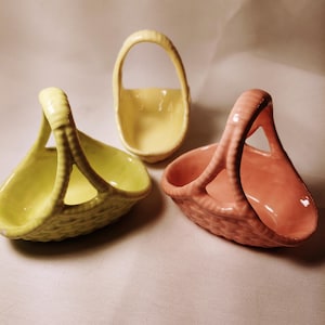 May include: Three small ceramic baskets with handles. The baskets are yellow, green, and pink.