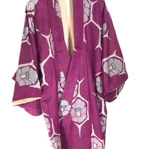 May include: A purple kimono with a white and blue floral pattern. The kimono is hanging on a hanger.