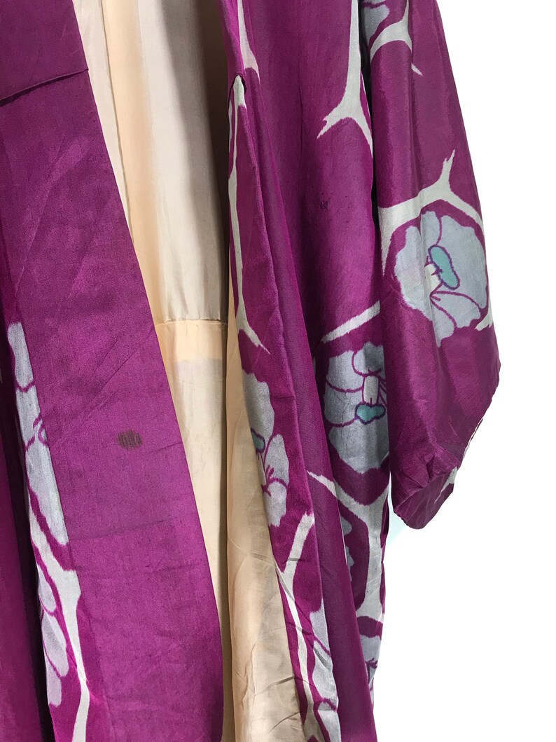 May include: A purple silk kimono with a white floral pattern. The kimono has a light beige lining.