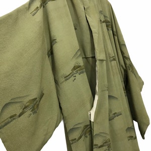 May include: A sage green Japanese kimono with a traditional landscape pattern. The kimono is made of a soft, lightweight fabric and has a relaxed fit.