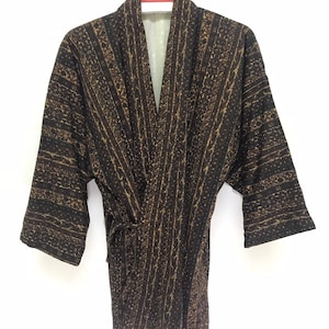 May include: A brown and gold patterned kimono robe with a tie belt. The robe has a V-neck and is hanging on a hanger with a "AKAGAMI" tag.