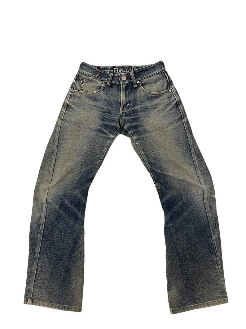Puede incluir: Vaqueros de mezclilla azul descolorido con un ligero corte de bota. Los vaqueros tienen un dise&ntilde;o cl&aacute;sico de cinco bolsillos, cierre de bot&oacute;n y cremallera, y un lavado descolorido para una apariencia desgastada. El texto "--FUNCTION--" est&aacute; en la cintura.