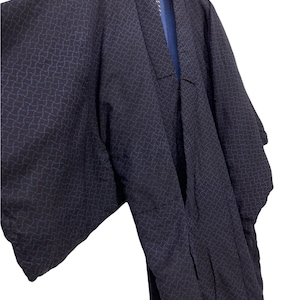 May include: A dark blue kimono with a geometric pattern in a lighter shade of blue. The kimono is hanging on a hanger.