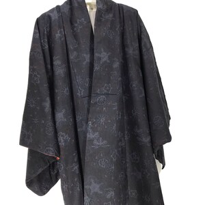 May include: A black kimono with a blue floral pattern. The kimono has a red trim on the sleeves and is hanging on a hanger.