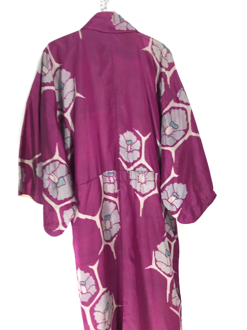 May include: A long, purple silk robe with a floral pattern. The robe has a traditional Japanese style with wide sleeves and a collar.