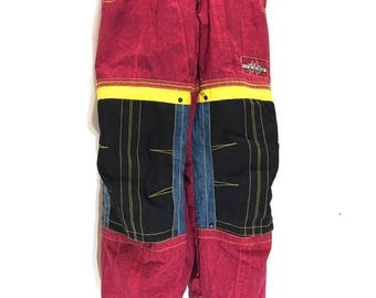 May include: Red ski jumpsuit with black and blue accents and yellow trim. The jumpsuit has a zipper down the front and a logo on the right leg that says "Mountain Extreme".